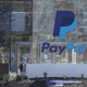 A man walks by a large sign with the PayPal logo on it in front of the PayPal headquarters in San Jose, California.